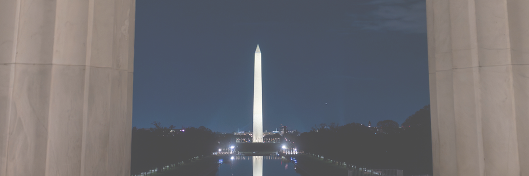 washington monument seen at night through two columns