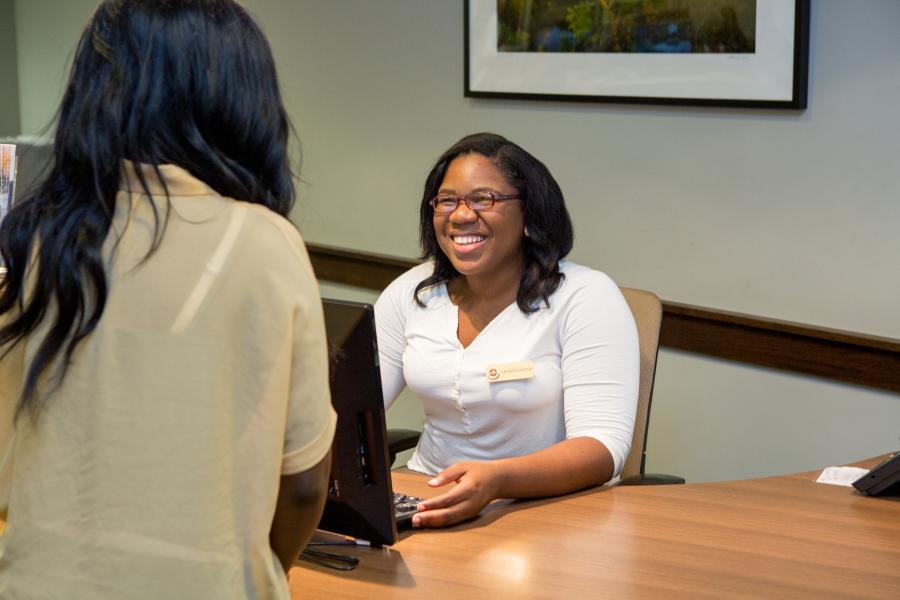 Two people speaking at a desk, seemingly a job interview
