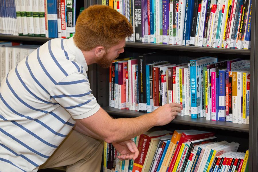 A person grabbing a book from a shelf